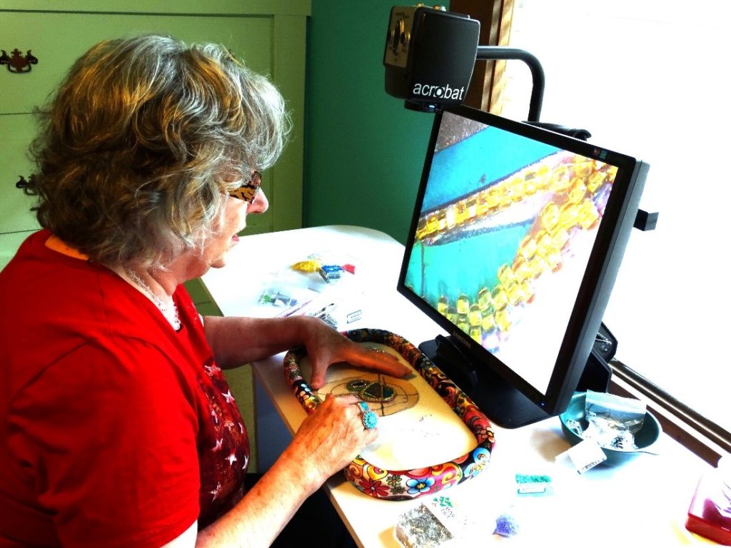 woman using an acrobat video magnifier to work on jewelry piece