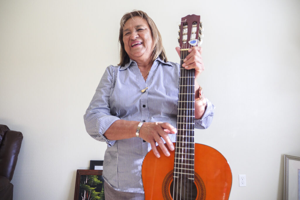woman smiling and playing guitar