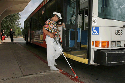 Person boarding paratransit bus using white cane
