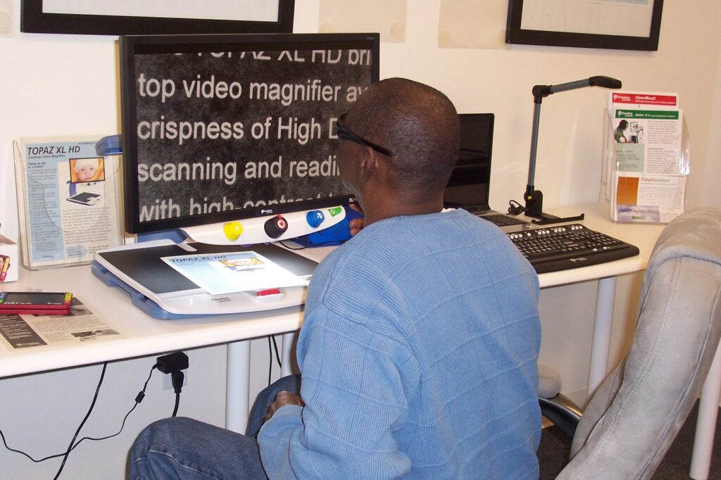 Man using desktop magnifier with white on black enlarged print